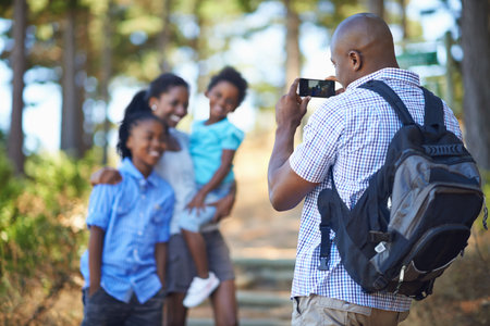 Capturing memories of a great outing. a father taking a picture of his family while out hiking in the woods.の写真素材