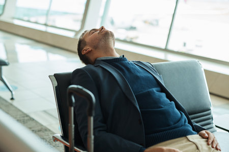 Airport, travel and tired businessman sleeping while waiting to board his plane for work in city. Exhausted, rest and professional corporate male employee taking nap while traveling with flight delayの写真素材