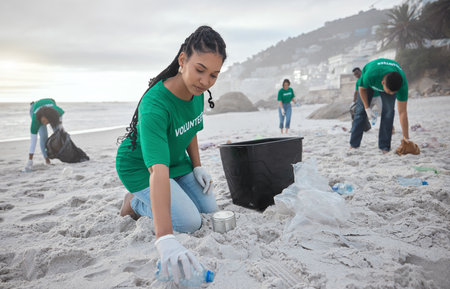 Teamwork, cleaning and recycling with black woman on beach for sustainability, environment and eco friendly. Climate change, earth day and nature with volunteer and plastic for community serviceの写真素材