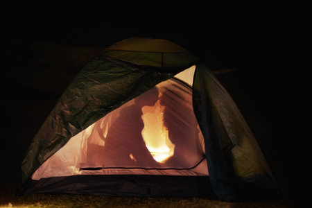 Camping romance. Silhouette view of a young couple kissing in a tent.の写真素材