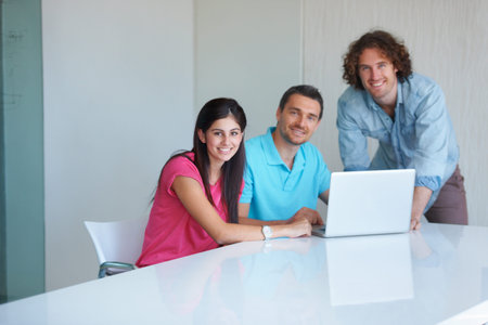 Weve got deadlines to meet and targets to beat. three coworkers gathered around a laptop in the...