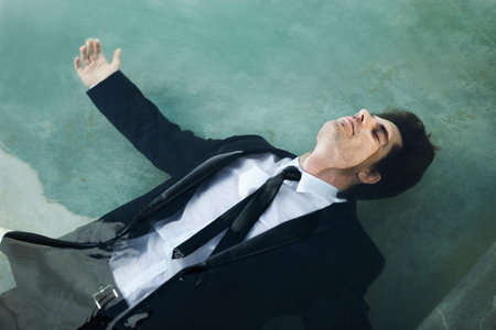 This boat is about to sink...A young businessman wearing a suit while floating in a pool of water -...