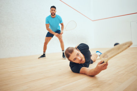 Two athletic squash players playing match during competitive court game. Fit active mixed race and caucasian athlete competing during training challenge in sports centre. Sporty men in championshipの写真素材