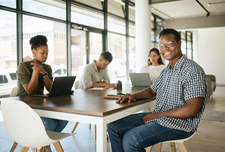 Group of diverse business people working in an office. Happy smiling business man leader manager looking at the camera while sitting at a table with his colleagues working in the backgroundの写真素材