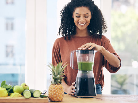 Blender, smoothie and black woman with green diet, detox and healthy morning breakfast in kitchen with fruits. Vegetables, food and young person or nutritionist with nutrition drink for vegan proteinの写真素材