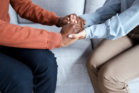 Holding hands, black couple and therapy help on sofa for support, solidarity and listening for love in relationship. Man, woman and couch for helping hand at psychology, consultation or trust problemの写真素材