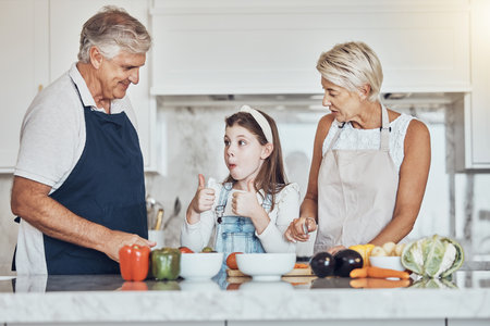 Thumbs up, grandparents or child cooking in kitchen as a happy family in a house with healthy vegetables at dinner. Grandmother, old man or girl with a yes, like or good hand sign helping with dietの写真素材