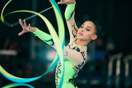 Sports, gymnastics and female performing with a ribbon for a competition or training in sport arena. Fitness, athlete and woman practicing for balance, endurance and flexibility exercise for routine.の写真素材