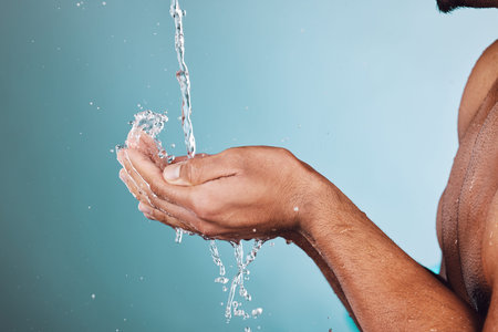 Man, water splash and hands in shower for skincare hygiene, wash or hydration against a studio...