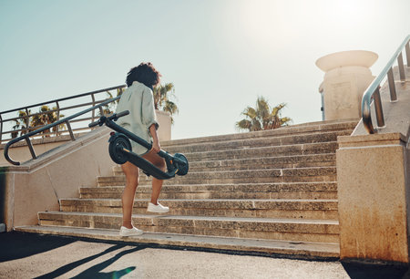 Walking, scooter and a black woman in the city using eco friendly transport to commute from the...