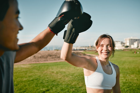 Woman, personal trainer and boxing high five for win, achievement or success outdoor in nature park....