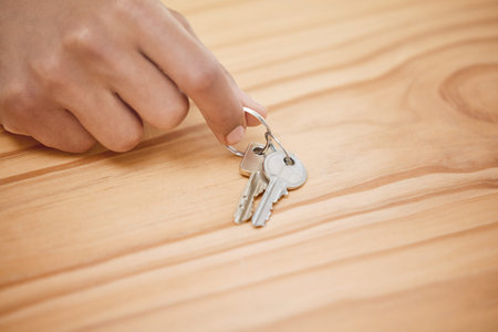 Can I take this now. an unrecognisable man taking a set of house keys off a wooden table.