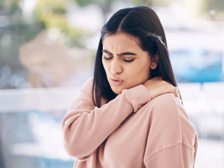 Neck, pain and mockup with an indian woman holding her shoulder on a glass background while suffering from cramp. Medical, anatomy or muscle and an attractive young female struggling with an injuryの写真素材