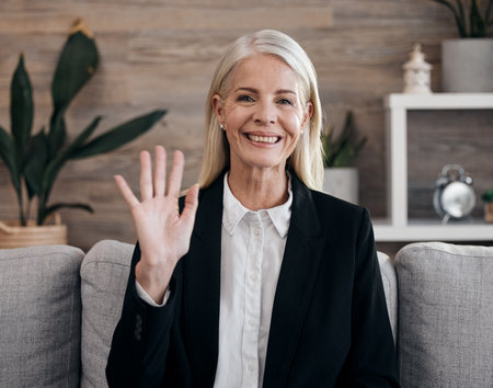 Video call, portrait and psychologist woman wave hello for virtual consultation, mental health therapy or counseling. Senior psychology expert, professional person or employee in online communicationの写真素材