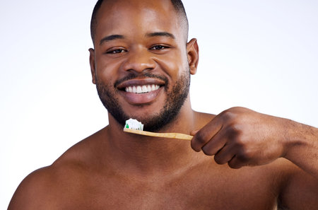 Keeping my smile nice and shiny. Studio portrait of a handsome young man brushing his teeth against...