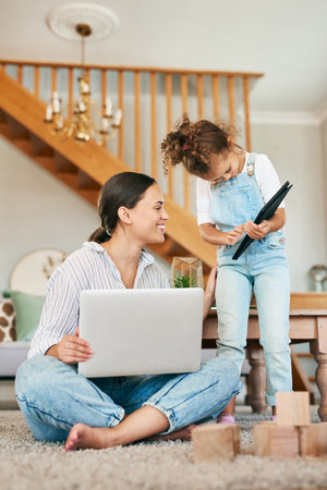 Look at the high score I made, Mom. a mother and her little daughter using digital devices at home.の写真素材