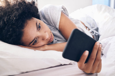Phone, social media and a black woman lying in bed in the morning after waking up on the weekend....