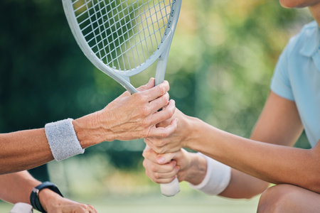 Hands together, tennis racket and coach with woman athlete, support and helping hand at training. Women, coaching and learning for sports, goals and motivation by blurred background outdoor for goalの写真素材