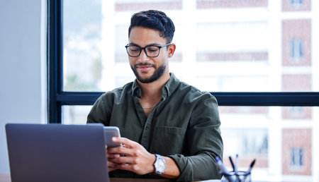 Just busy turning another day into a success. a young businessman using a cellphone while working in...