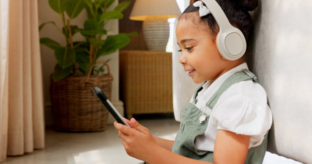Tablet game, headphones and relax child gaming, having fun or play online games on mobile device or digital tech app. Kid entertainment, youth lifestyle and young gamer girl playing on ui touchscreenの写真素材
