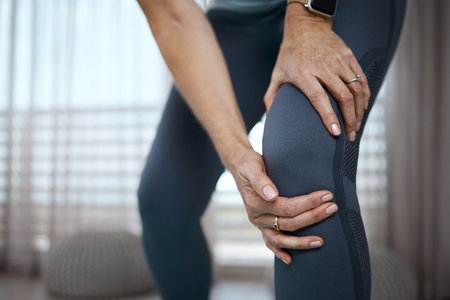 Push through, well stare at the ceiling tomorrow. Cropped closeup of an unrecognizable woman experiencing pain in her knee while exercising at home.の写真素材