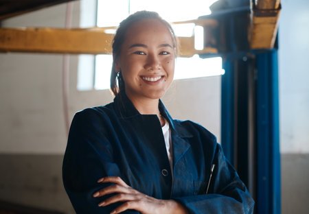 Im an expert on the subject of cars. a female mechanic posing with her arms crossed in an auto repair shop.の写真素材