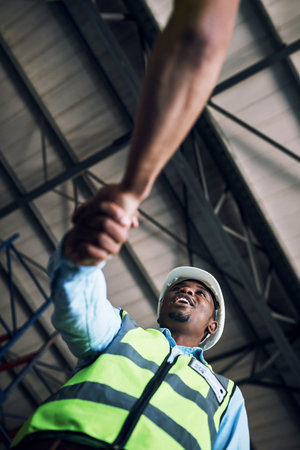 Our commitment to our clients keep the doors open. two builders shaking hands at a construction...