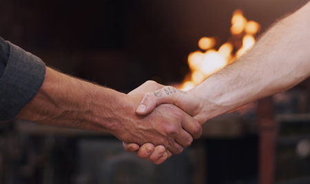 Good partnerships are made of steel. two men shaking hands in a workshop.の写真素材