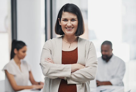 Pregnancy is going well and so is business. Portrait of a confident pregnant businesswoman having a team meeting in a modern office.の写真素材