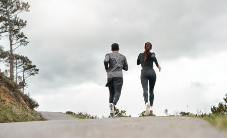 Running is second nature to us. Full length shot of two unrecognizable athletes bonding together during a run outdoors.の写真素材