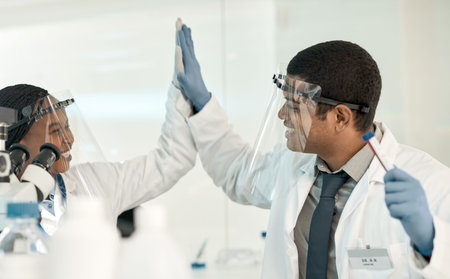 Case solved, case closed. two scientists giving each other a high five while working together in a...