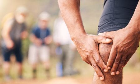 Knee pain, injury and hands of senior black man after hiking accident outdoors. Sports, training hike or elderly male with fibromyalgia, leg inflammation or arthritis, broken bones or painful musclesの写真素材