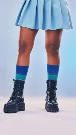 Boots, gen z fashion and legs of a young women in a studio with rock and pastel punk aesthetic. Isolated, blue background and colorful clothes of a person with creative cyberpunk and unique clothingの写真素材