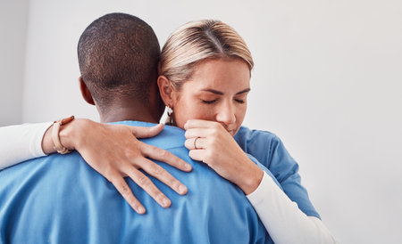 Comfort, support and doctors hugging in the hospital after the death of a patient in surgery. Healthcare, sad and medical workers embracing with care, love and compassion in the medicare clinic.の写真素材