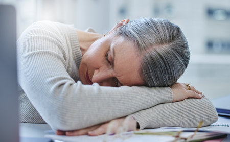 I need to take a break. a mature businesswoman feeling exhausted and sleeping on her desk in her office.の写真素材