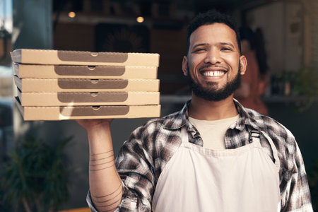 Just what the pizza-man ordered. a handsome young man standing outside his restaurant and holding a stack of pizza boxes.の写真素材