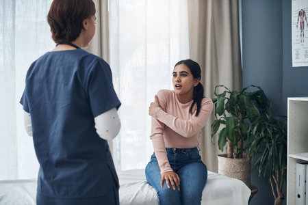 It also hurts at the back. a young female patient talking to a doctor in an office.の写真素材