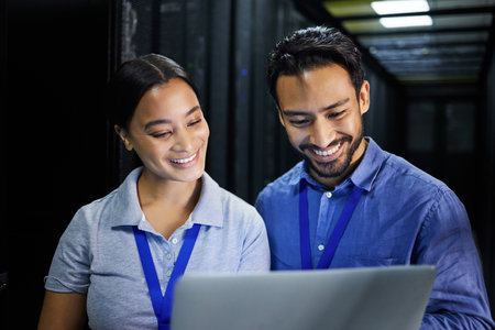 People, happy or laptop in server room, IT engineering or software programming for cybersecurity, analytics or database safety. Smile, man or data center woman on technology in teamwork collaborationの写真素材