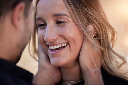 Love, happy and woman looking at her boyfriend while on romantic date for valentines day. Happiness, smile and man holding the face of girlfriend to bond with intimacy, affection and romance outdoorsの写真素材
