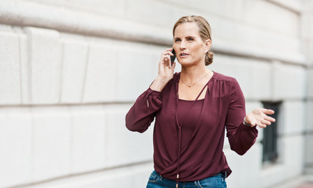 Dont be afraid to go after what you want. a mature businesswoman using a smartphone against an urban background.の写真素材