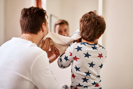 Getting fresh for the day. a man and his young son drying their faces after shaving.の写真素材