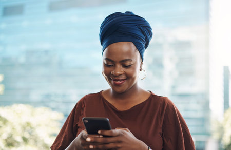 Its like a desk that fits into your pocket. a young businesswoman using a smartphone against a city...