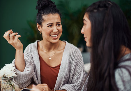 Girl talk is good for growing a bond. young sisters spending quality time at a cafe.の写真素材