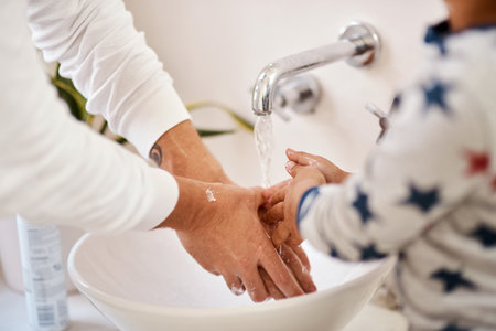 Wash up because its good for your health. a man and his son washing their hands in the bathroom.の写真素材