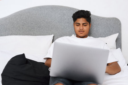 You name it, and there is a blog about it. an young man using his laptop while lying on his bed.の写真素材