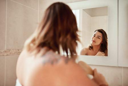 Knots are not welcome here. an attractive young woman brushing her hair during her morning beauty...