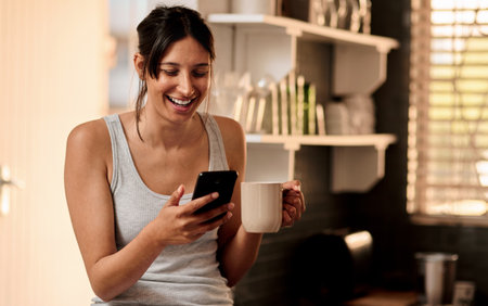 Good coffee and a good laugh makes a perfect morning. a young woman using a smartphone while...
