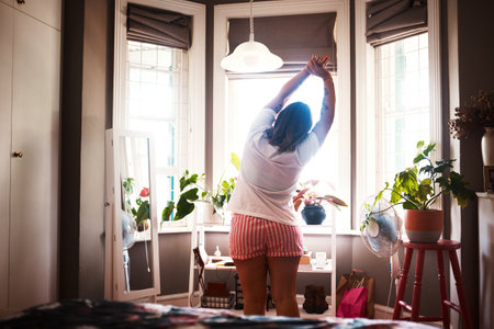 Its a beautiful day out there. Rearview shot of a young woman stretching at home.の写真素材