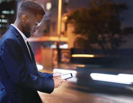 Phone, business and black man in city at night, street or outdoors in town for texting. 5g mockup, technology and male employee with smartphone for social media, internet browsing or web scrolling.の写真素材