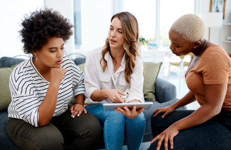 Should we go through with this plan. a group of businesswomen working together on a digital tablet in an office.の写真素材